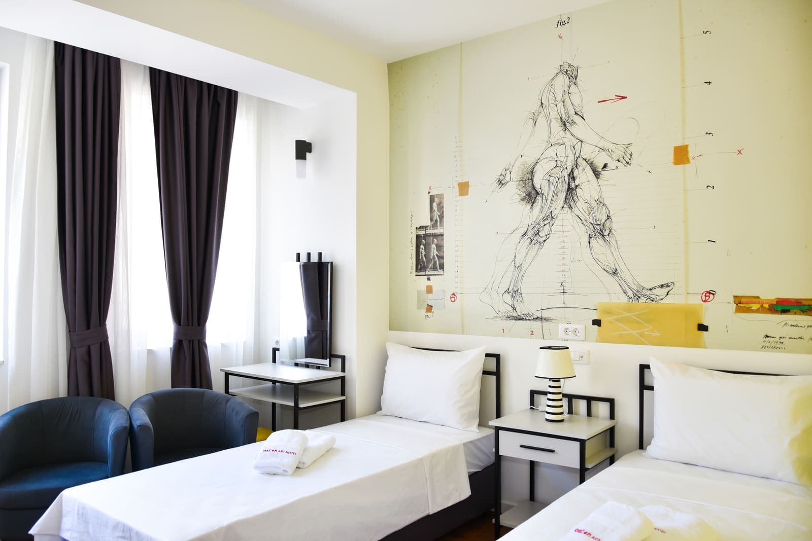 A sunlit twin room with mural artwork